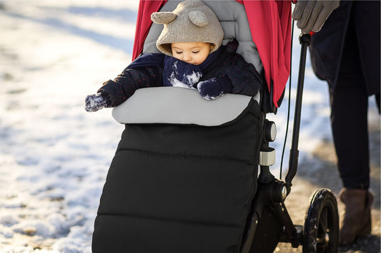 Bébé au chaud dans une chancelière poussette noire  en hiver