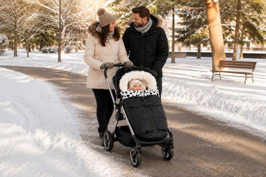 chancelière bébé hiver avec bébé installé dans une poussette pendant une promenade en famille dans un parc enneigé, illustrant le confort et la protection contre le froid 