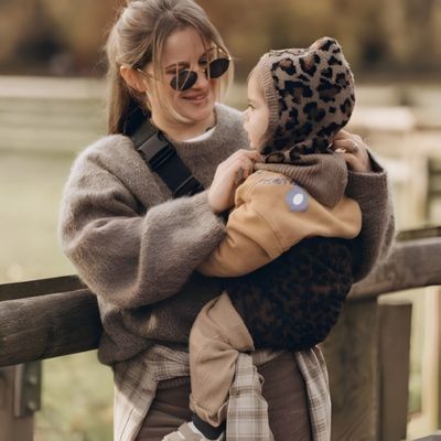 maman portant son enfant avec le porte bebe léopard