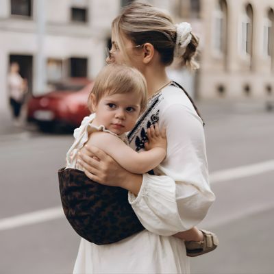 maman tenant son enfant dans le porte bebe léopard en ville