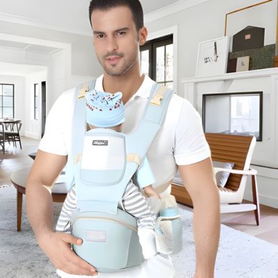 papa portant bebe face a face dans salon avec porte bebe ergonomique vert