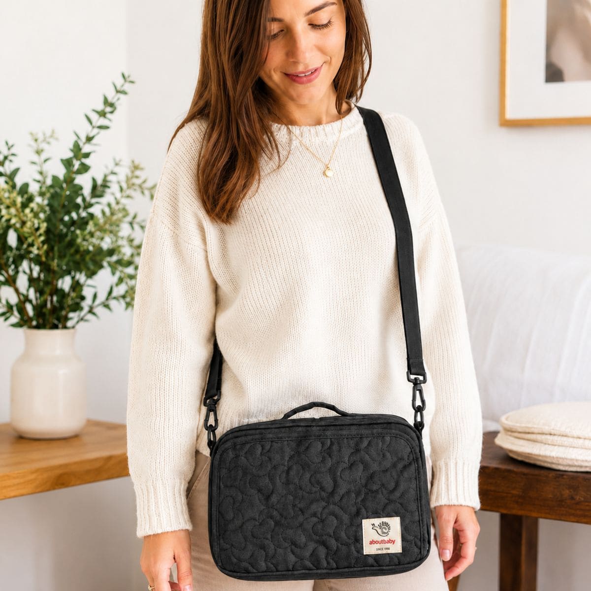 organisateur poussette Nomade noir porté en bandoulière par une maman pour transporter les essentiels de bébé.