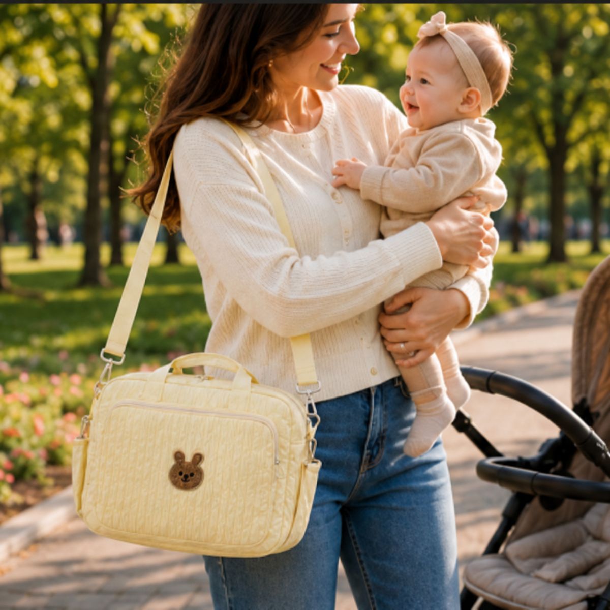 Sac à langer Petit Câlin beige porté en bandoulière par une maman avec son bébé