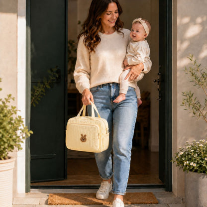 Sac à langer Petit Câlin beige porté à la main par une maman avec son bébé
