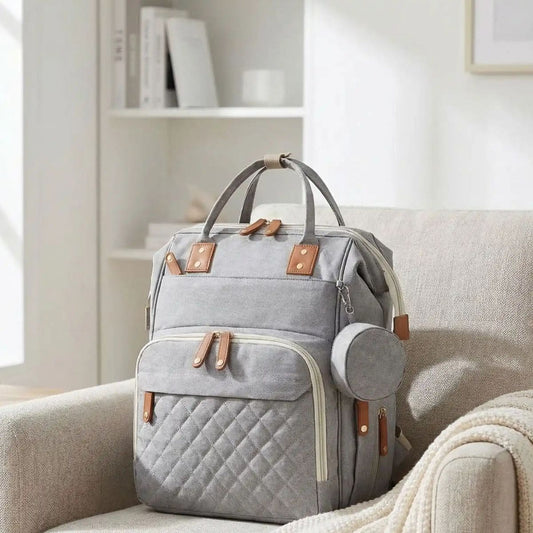 Sac à dos à langer Urban Baby gris posé sur un canapé dans un salon lumineux