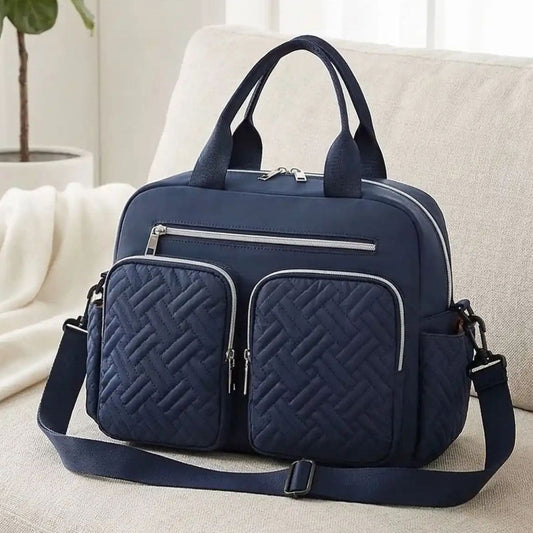 Sac à langer Élégance Organisée bleu foncé posé sur un canapé dans un salon